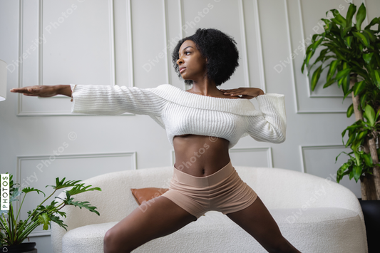 Young woman doing virabhadrasana yoga pose in living room