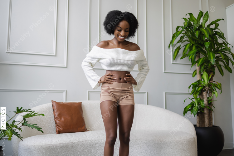 Smiling woman standing with hands on hips in living room