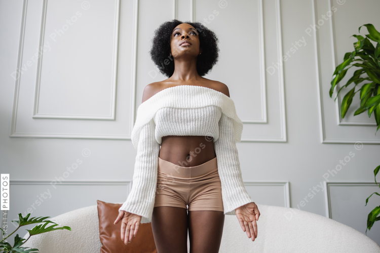 Young woman doing tadasana yoga pose in living room