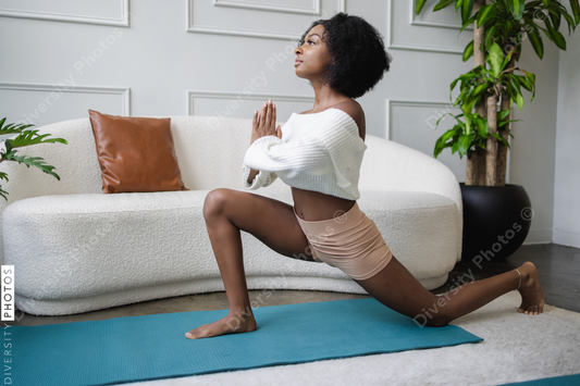 Young African American woman doing lunge yoga pose in living room