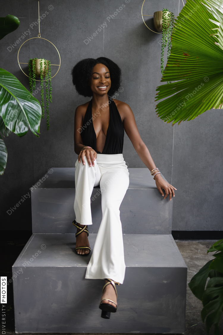 Elegant young woman sitting on steps among plants