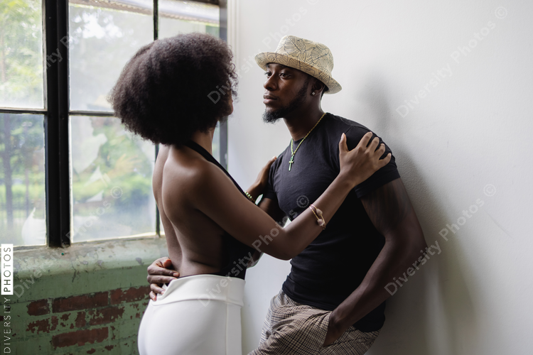 Young couple standing next to window and embracing