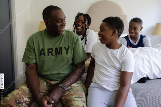 Black military dad smiling with kids in bedroom at home