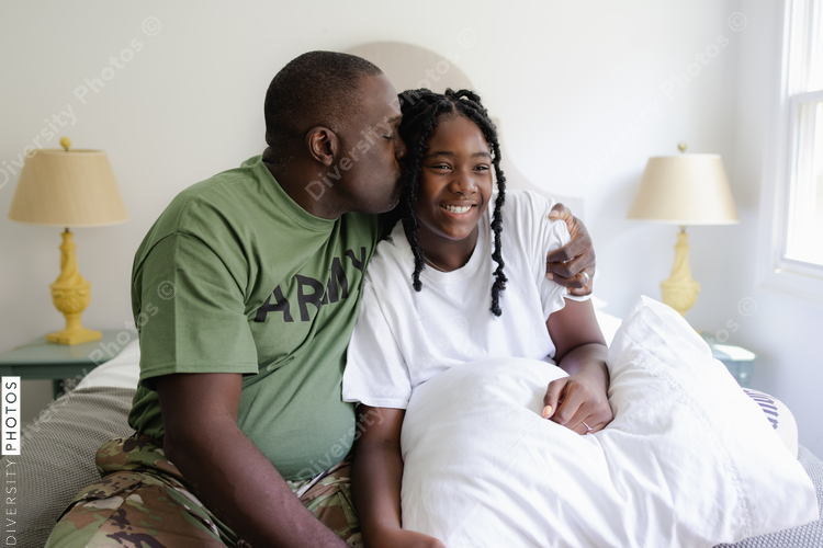 Black dad kissing daughter on cheek, army