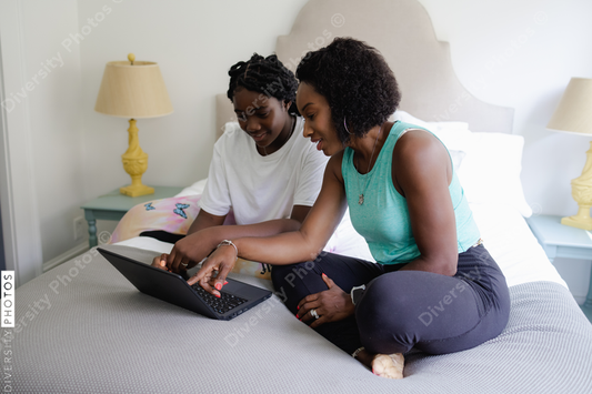 African American mother helps daughter with homework, on laptop