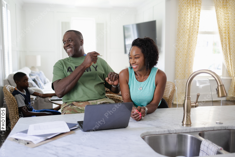 Black military couple laughing at home, while working