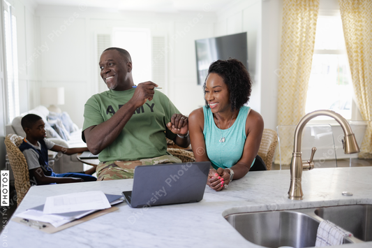 Black military couple laughing at home, while working