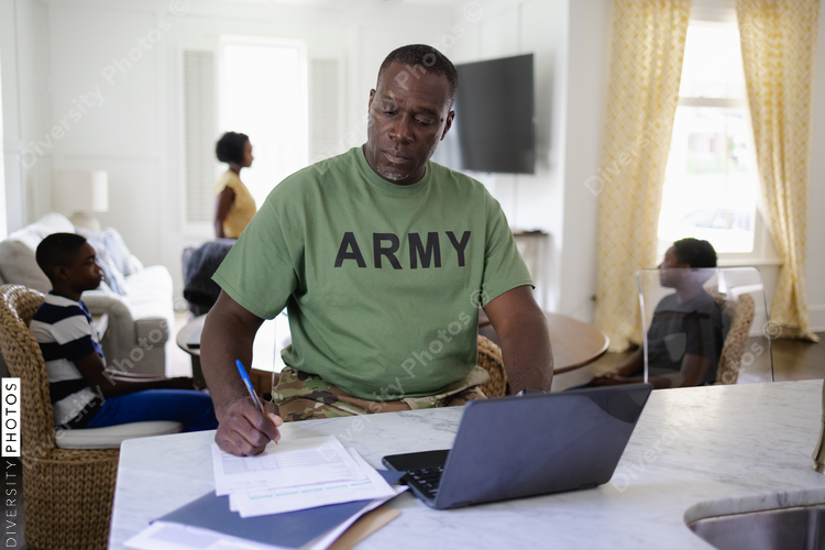Focused African American man working with family in background