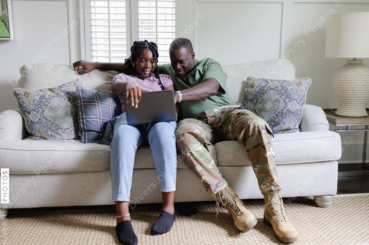Black dad helps daughter with homework on laptop