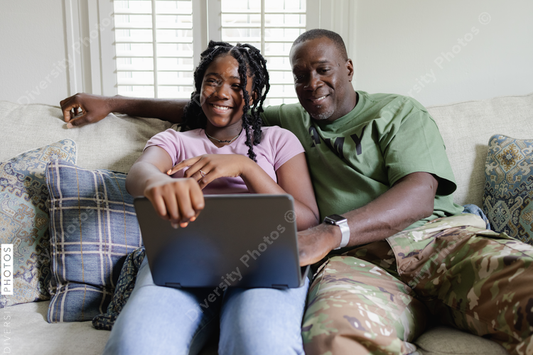 Black dad helps daughter with homework on laptop