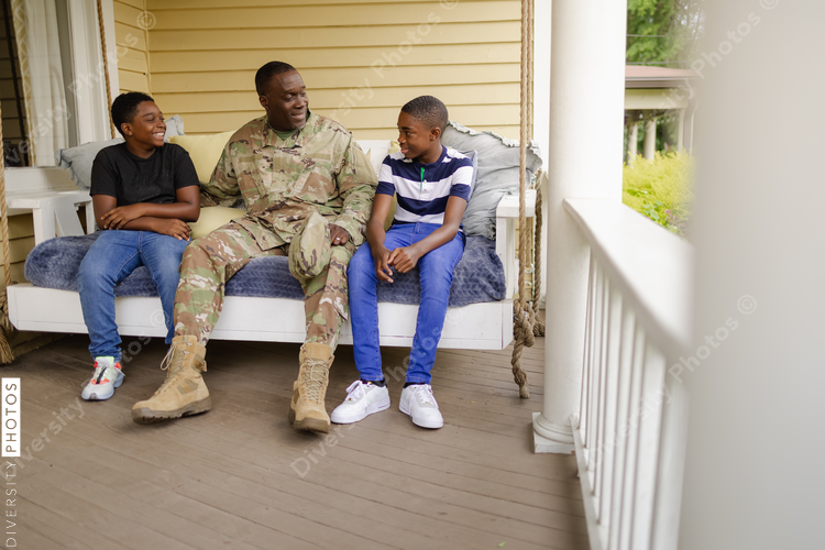 Military dad talks with sons on front porch swing