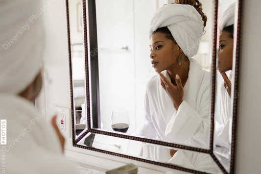 African American Woman in bathrobe looking in bathroom mirror