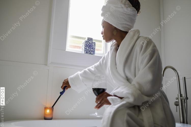 Woman in bathrobe igniting bath candle