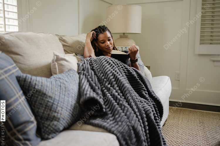 Woman sitting on sofa, reading book