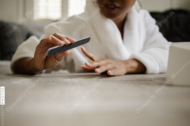 Woman in bathrobe doing manicure, close up