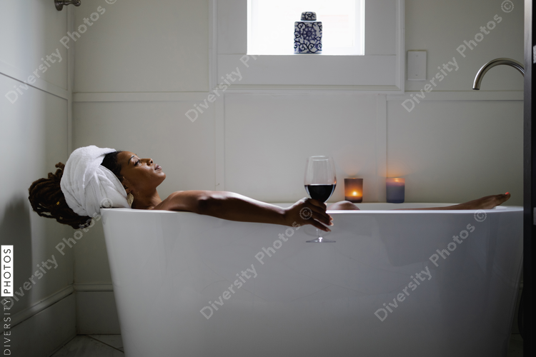 Black Woman taking relaxing bath with glass of wine