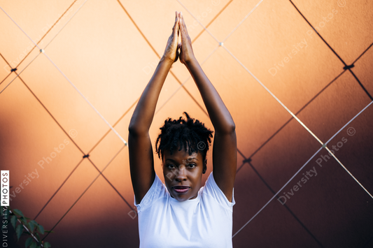 Black woman doing tree pose at sunset