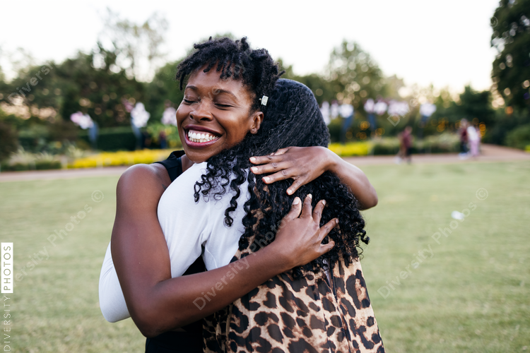 Black women sisterhood, smiling outdoors, embracing, hugging 