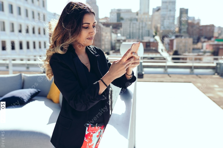 Businesswoman using smartphone while standing on office rooftop