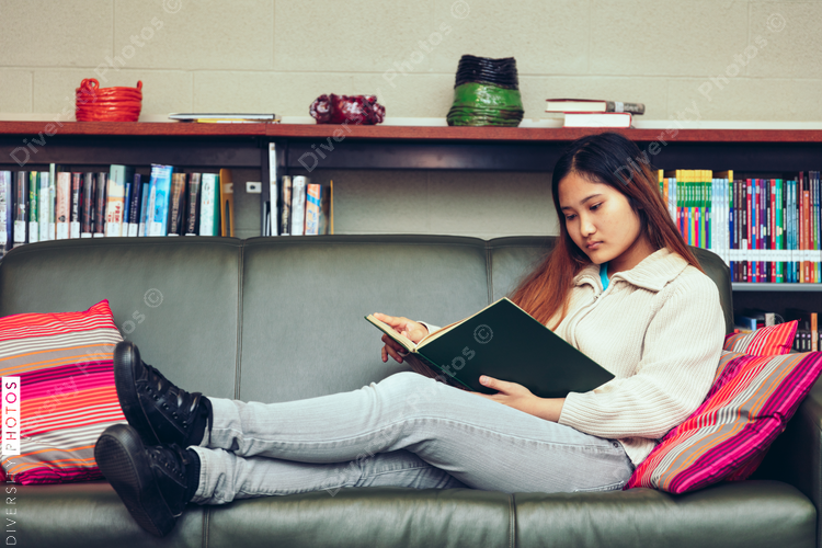 Teenage girl studying in library while sitting on the sofa