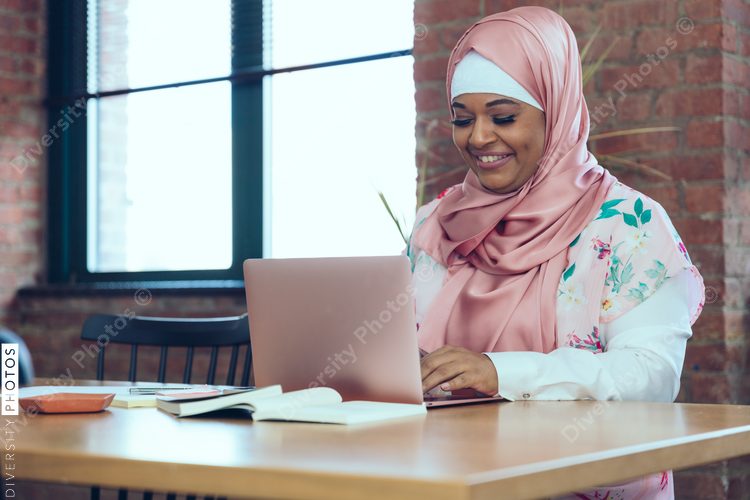 Smiling Businesswoman working on laptop while sitting in office