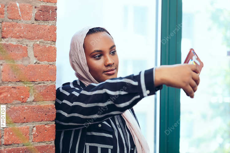 Businesswoman taking selfie while standing near window