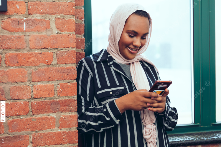 Smiling businesswoman using smartphone while standing near window