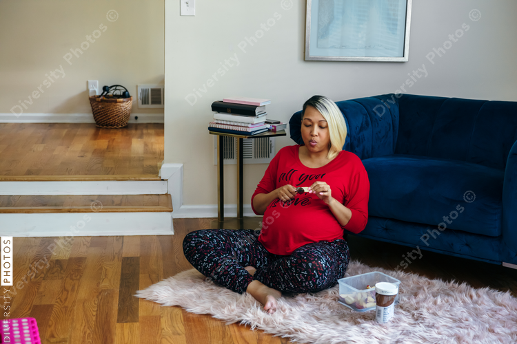 Pregnant black woman with blonde hair eating healthy snack at home