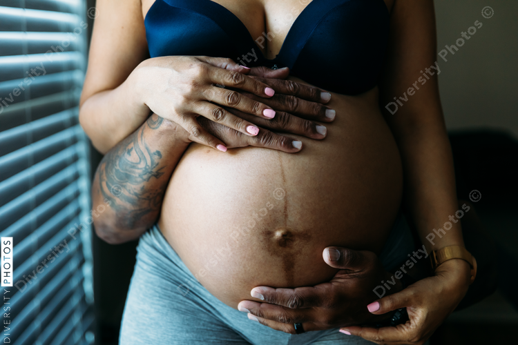 Black couples hands around belly in third trimester pregnancy