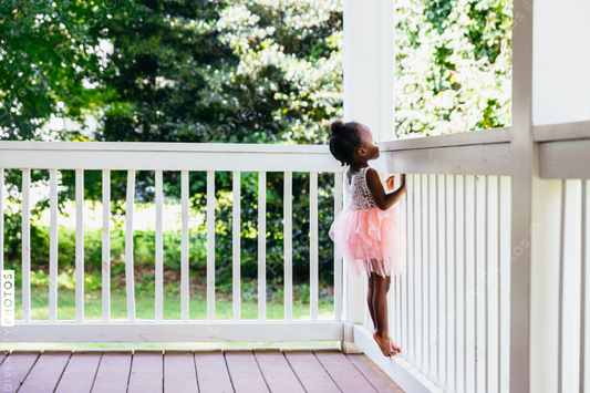 Young ballerina playing on front porch at home