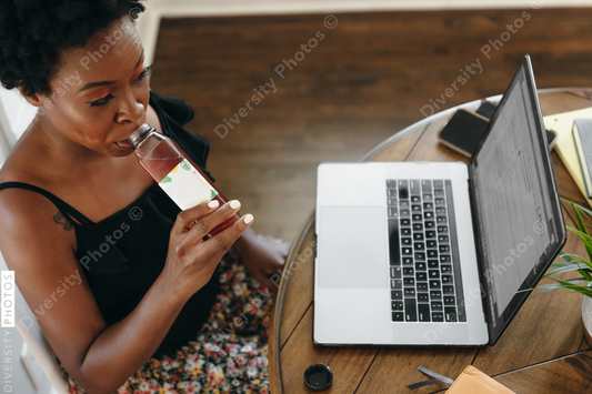 Woman working remotely from home drinking a healthy drink