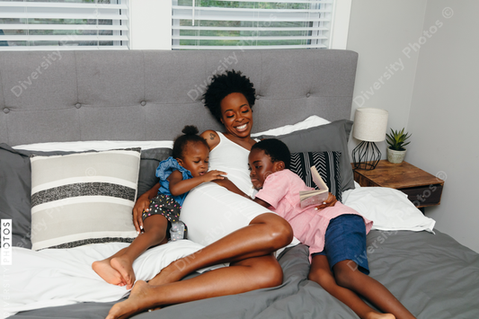 Black mother and her children embracing and cuddled in bed at home