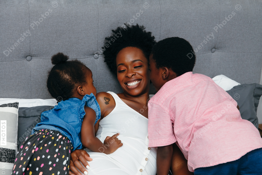 Black mother and her children embracing and cuddled in bed at home