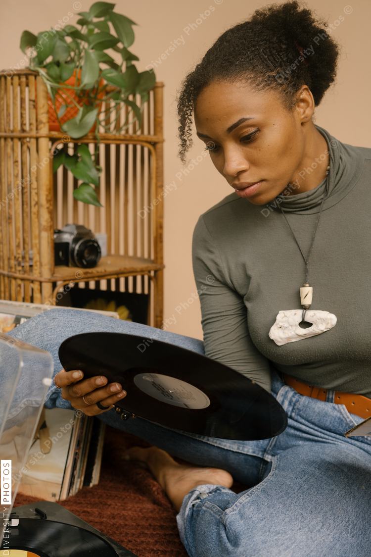 Black woman listening to music through vintage vinyl records