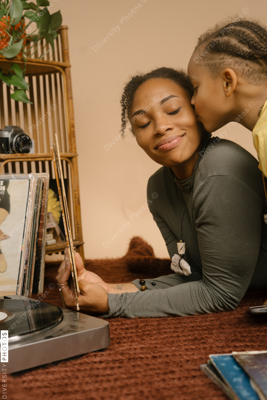 Black son giving mom a kiss on the cheek at home