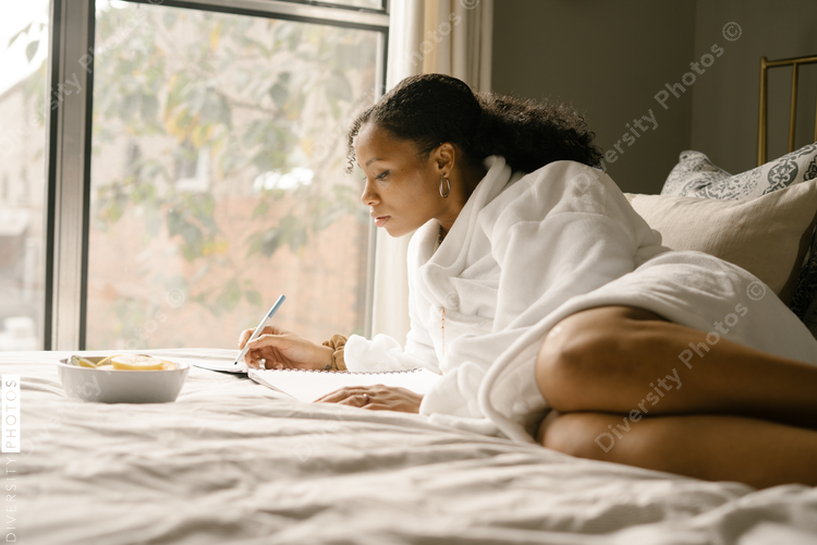 Black woman journaling at home in bed