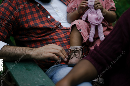 Black father and daughter sitting outdoors in backyard