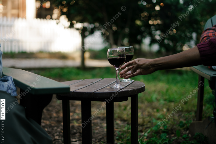 Black woman reaches for glass of red wine at party