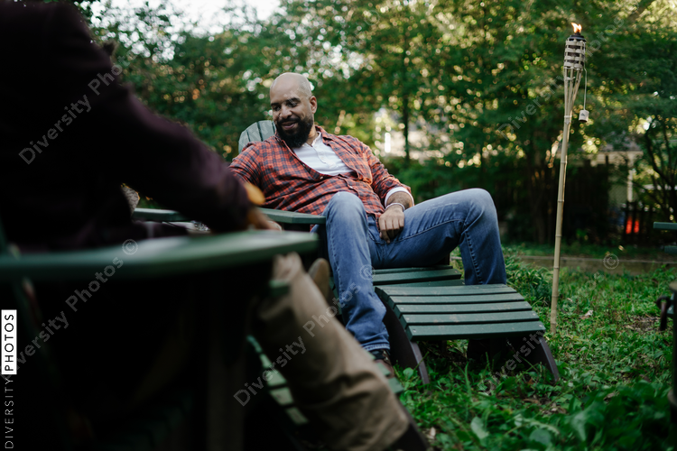 Friends together distanced at backyard party around firepit