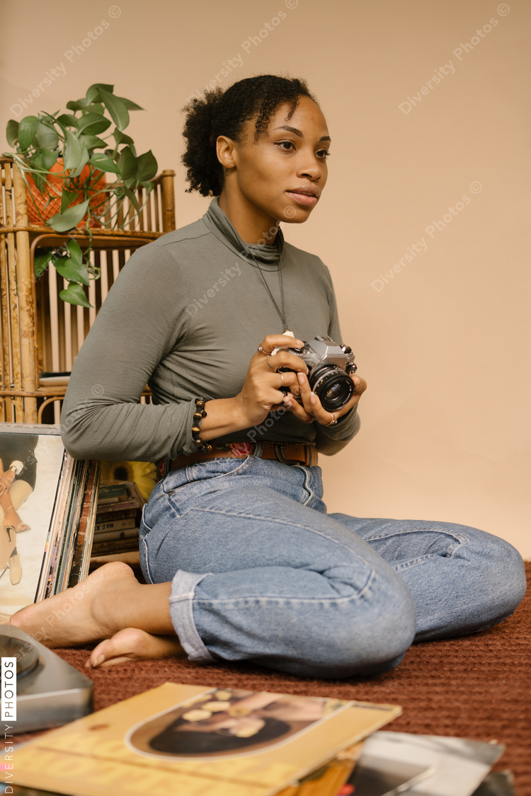 Portrait of woman holding camera while sitting at home