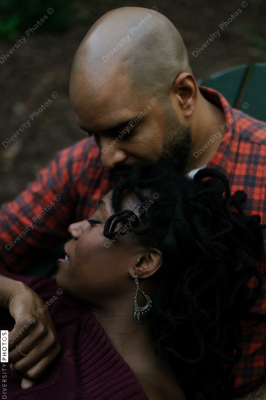 Black mand and woman in love outdoors in backyard sitting next to cozy firepit