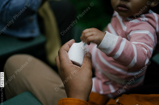 Black dad sharing food with baby daughter at party