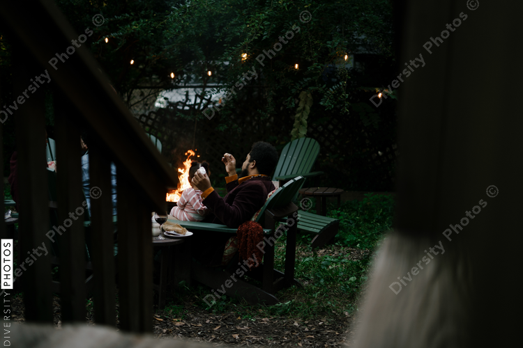 Friends gathered for evening party in backyard around firepit