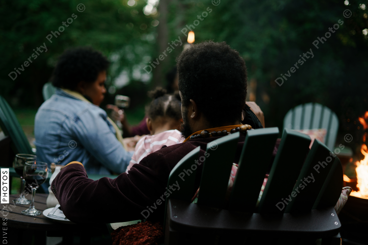 Friends gathered for evening party in backyard around firepit