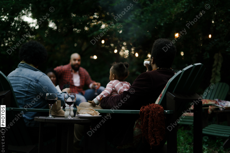 Friends gathered for evening party in backyard around firepit