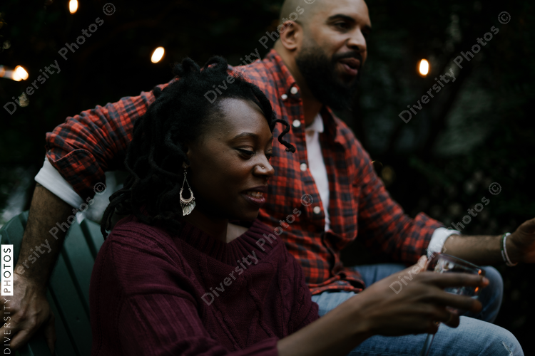 Black couple socializing and talking with friends at backyard party