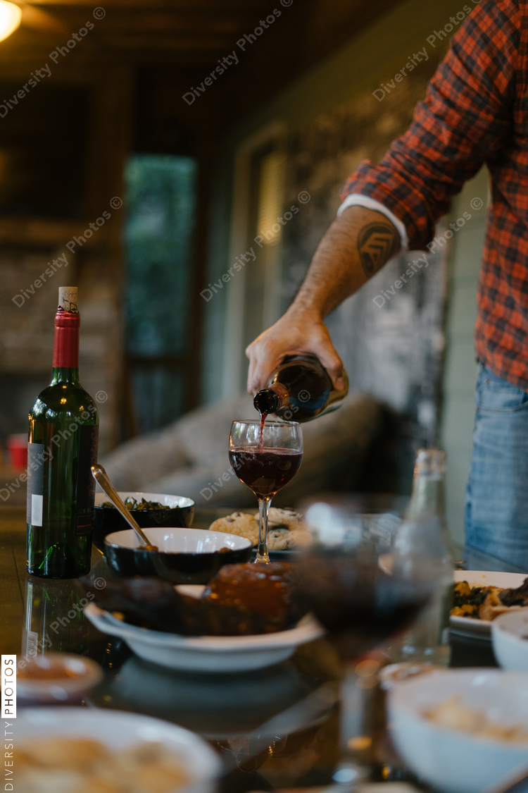 Man serving wine to friends at outdoor dinner party