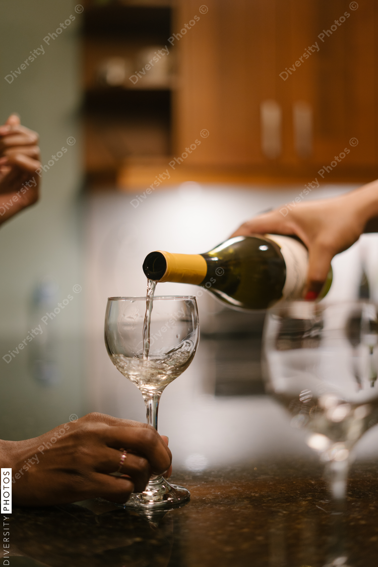 Friend pouring guest wine at house party