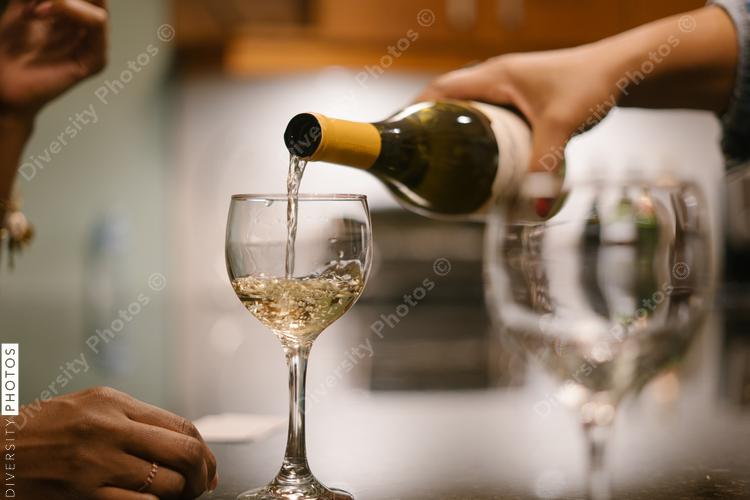 Friend pouring guest wine at house party