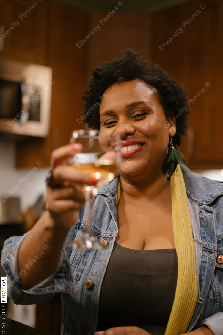 Black woman toasting with wine at a house party and get together with friends
